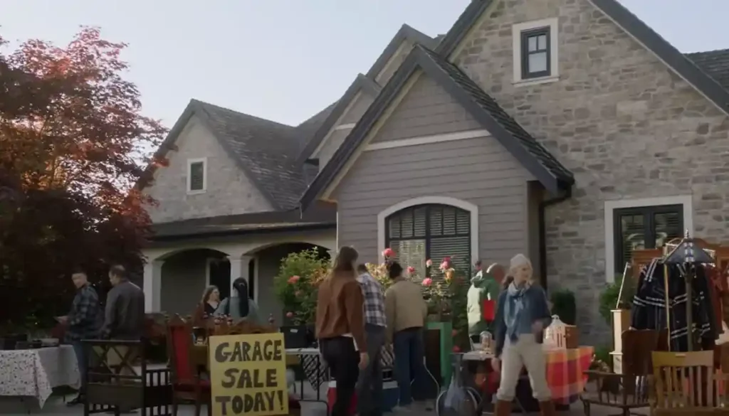 Where was Garage Sale Mysteries: Murder Takes the Stage filmed? Locations, Cast, and Everything Garage sale scene outside a stone house in Garage Sale Mysteries, with shoppers browsing furniture, clothing and household items.