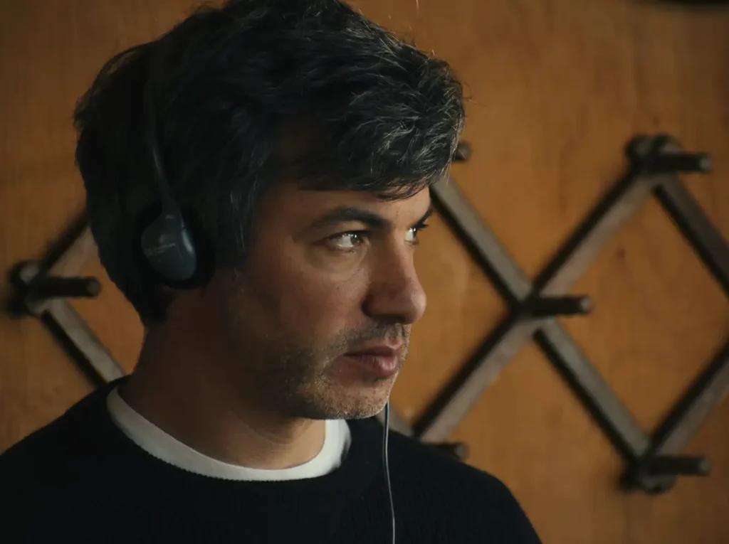 Nathan Fielder wearing headphones during an interview scene in Elizabeth Holmes documentary 2026