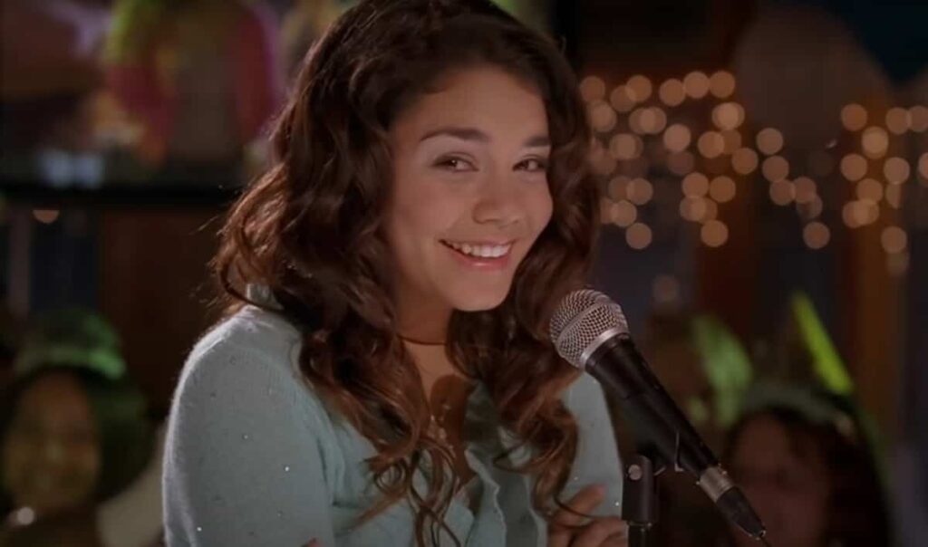 High School Musical showing a smiling Vanessa Hudgens as Gabriella Montez while singing with Zac Efron as Troy Bolton