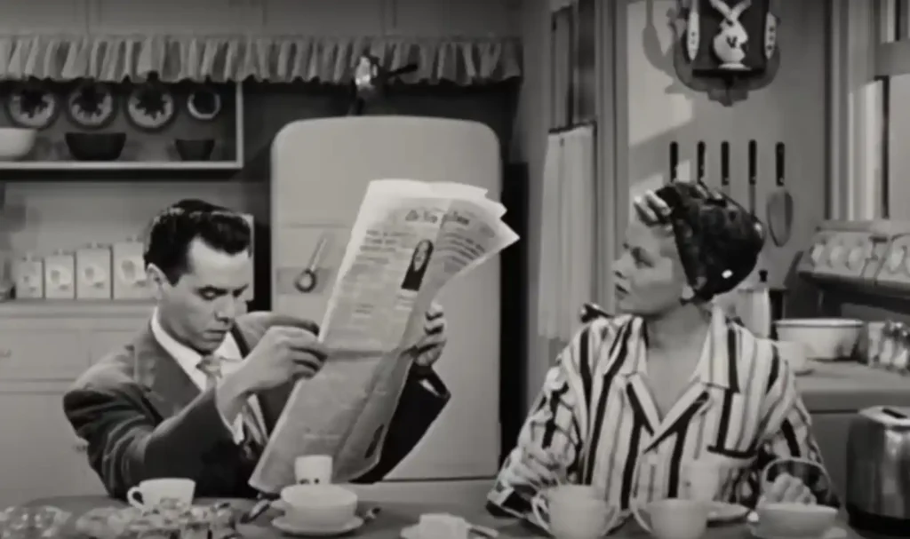 Lucy and Desi documentary showing Desi Arnaz reading newspaper with Lucille Balls looking at him in shock
