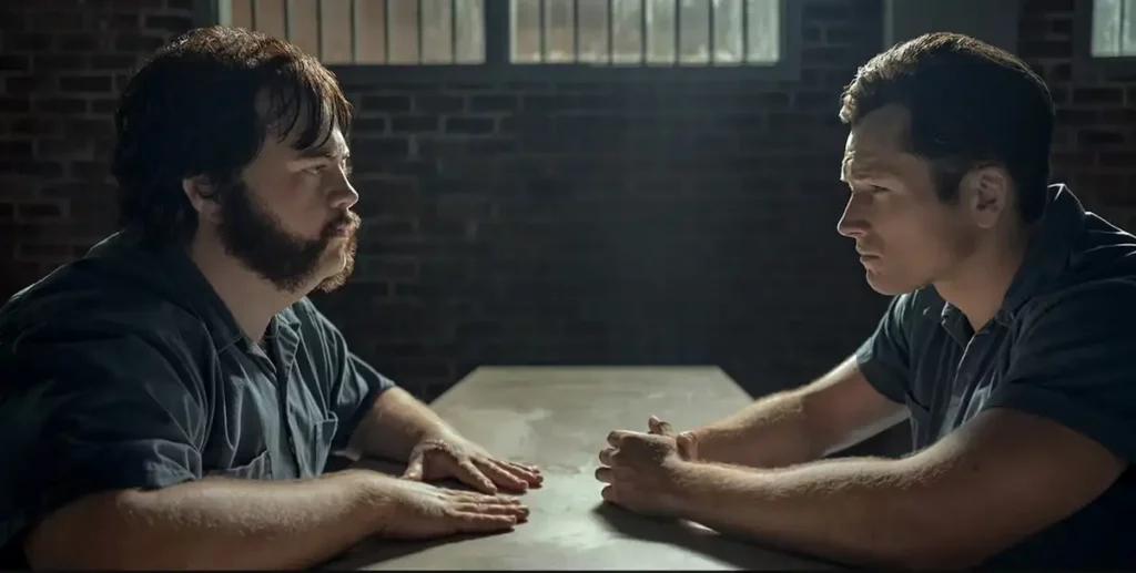 Black Bird series showing Taron Egerton talking with Paul Walter Hauser during a meeting in prison