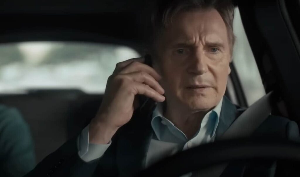 Liam Neeson as Matt Turner talking on a phone while driving car in Retribution movie
