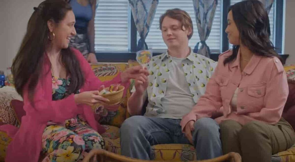 Jack Kilmer sitting on a sofa in the middle of Mariana Trevino and Emily Tosta in Bennie's Mexican house