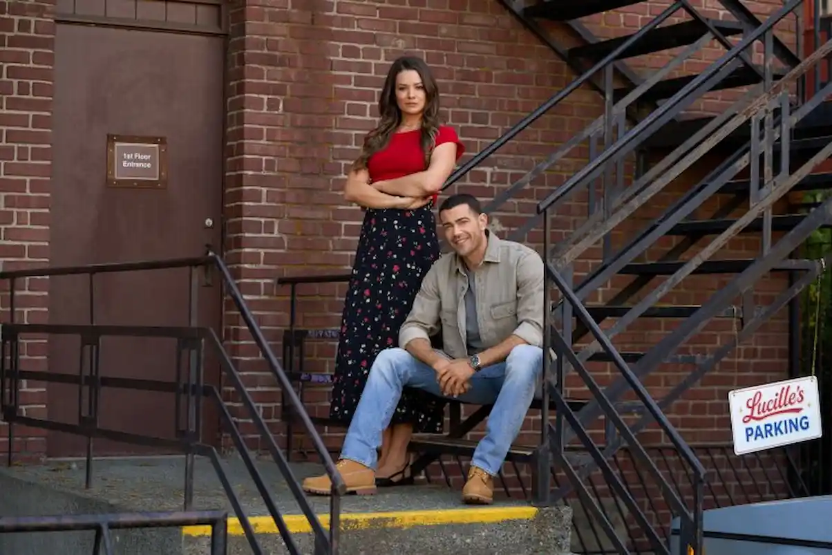 Where was Hallmark's 'Absolutely Devoted to You' filmed? Kimberley Sustad and Jesse Metcalfe pose on a brick building's fire escape stairs in a promotional photo for Hallmark's 'Absolutely Devoted to You,' with a 'Lucille's Parking' sign visible in the background