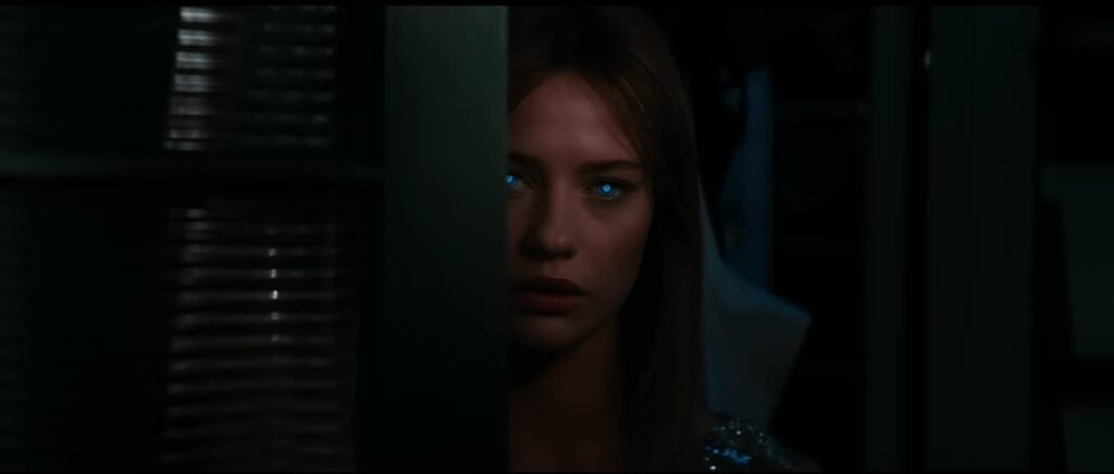 Lily Sullivan as SARA the AI android in Soulm8te 2026, peering around a dark doorway with glowing blue eyes