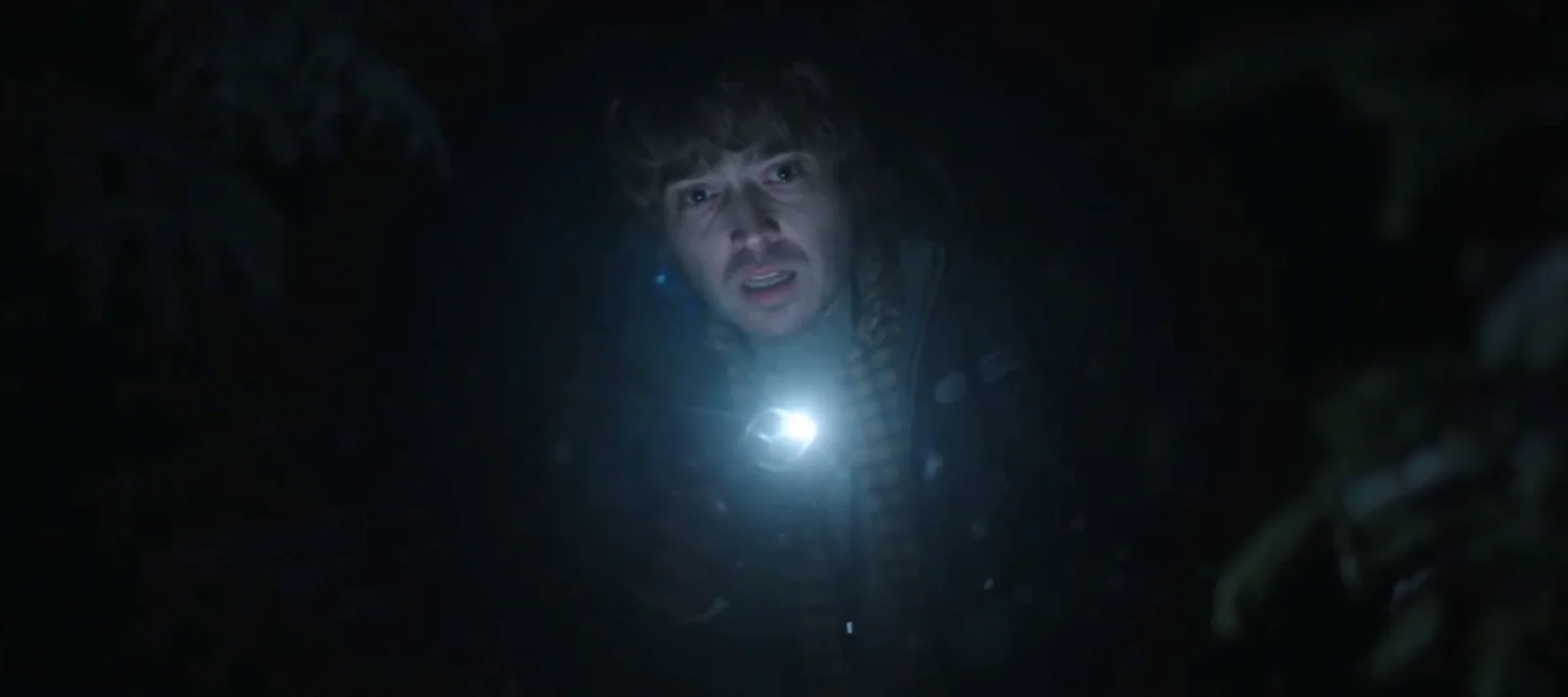 Where to watch Resident Evil (2026): Theaters, PVOD, Netflix, and Everything In Between Austin Abrams as Bryan searches through a dark forest at night, holding a bright flashlight in a tense scene from Resident Evil (2026).