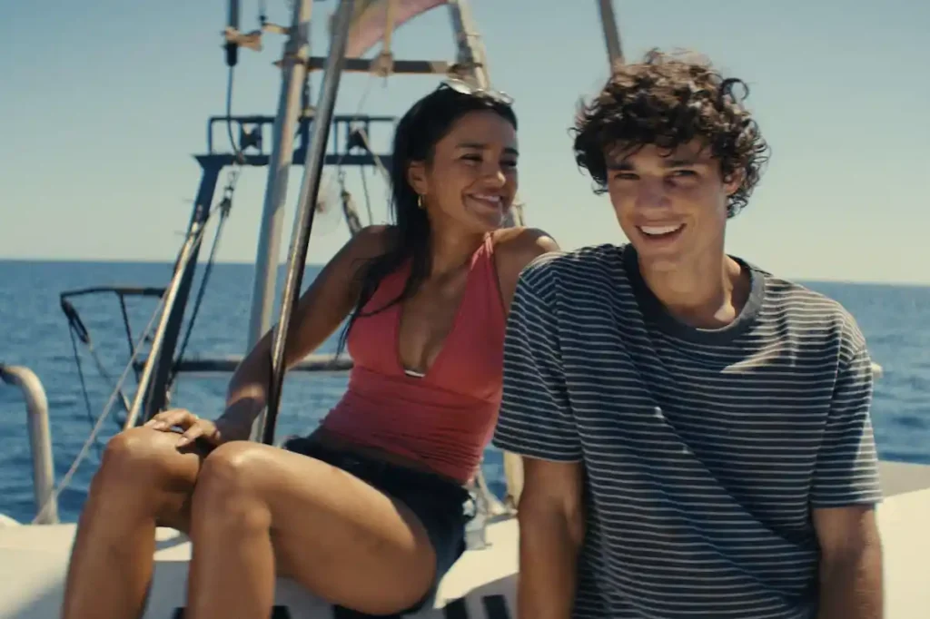 Maia Reficco and Fernando Lindez smiling together aboard a boat in The Last Sunrise, with the Mediterranean Sea in the background